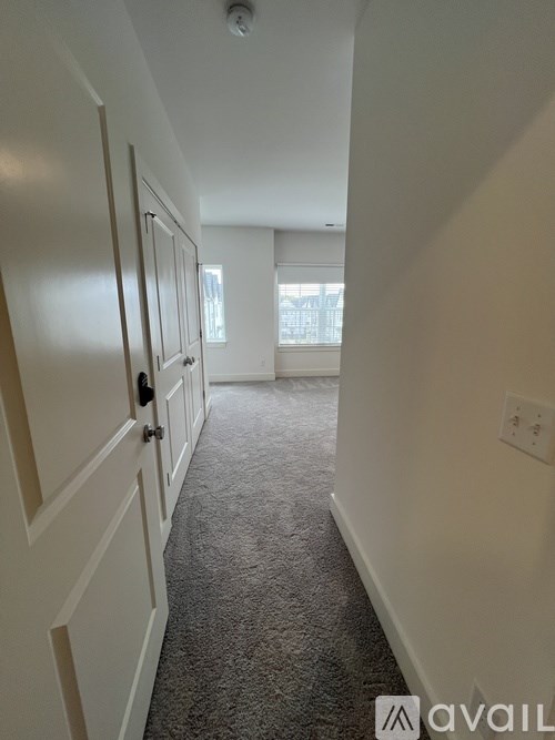 A hallway with a carpeted floor and white walls.