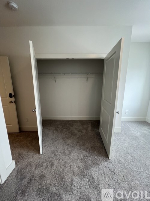 A bedroom with a carpeted floor and a large open closet.