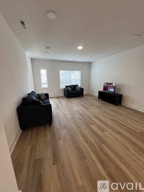 A living room with black furniture and wooden flooring.