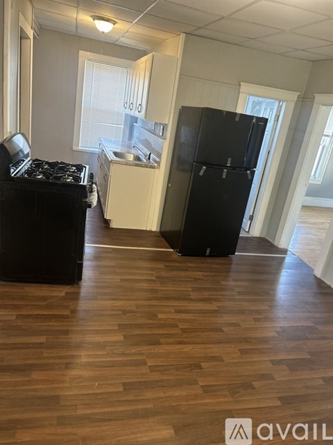 A black fridge in a kitchen with wooden floors.