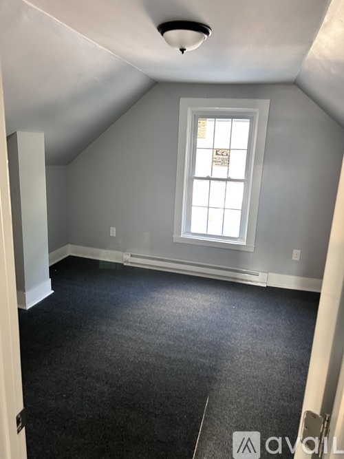 A room with a window and a carpeted floor.