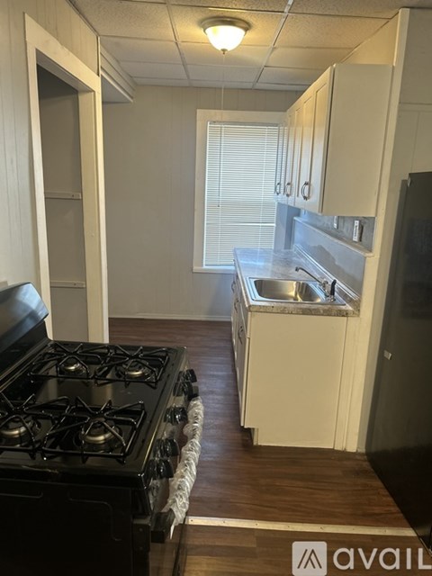 A kitchen with a black stove top oven and a white cabinet with a microwave above it.