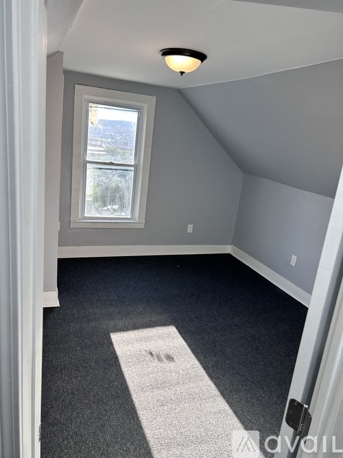 A room with a window and a carpeted floor.