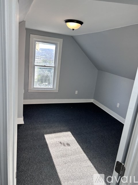 A room with a window and a carpeted floor.