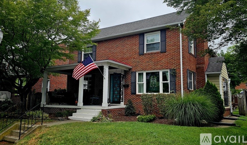 A red brick house with a green door and an American flag on the porch.