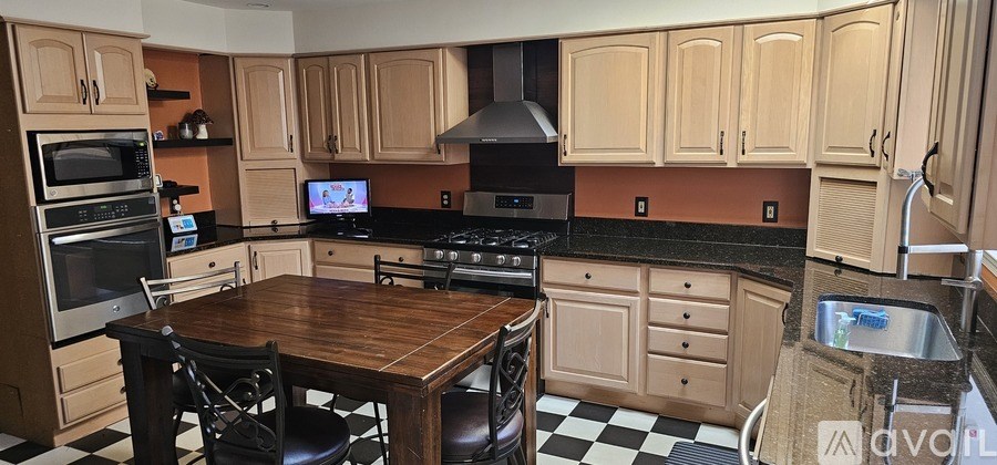 A kitchen with wooden cabinets and a black and white checkered floor.