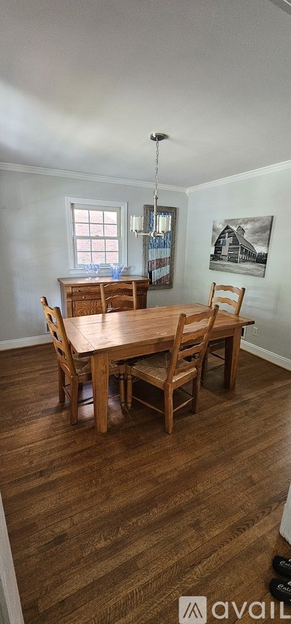A wooden dining table with four chairs is in a room with wooden flooring.