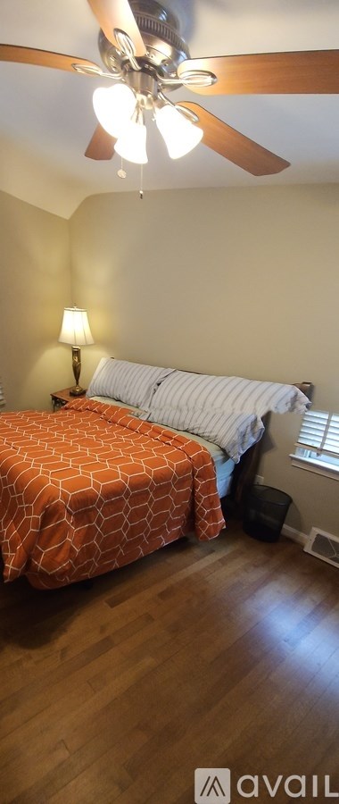 A bedroom with a bed and a ceiling fan.