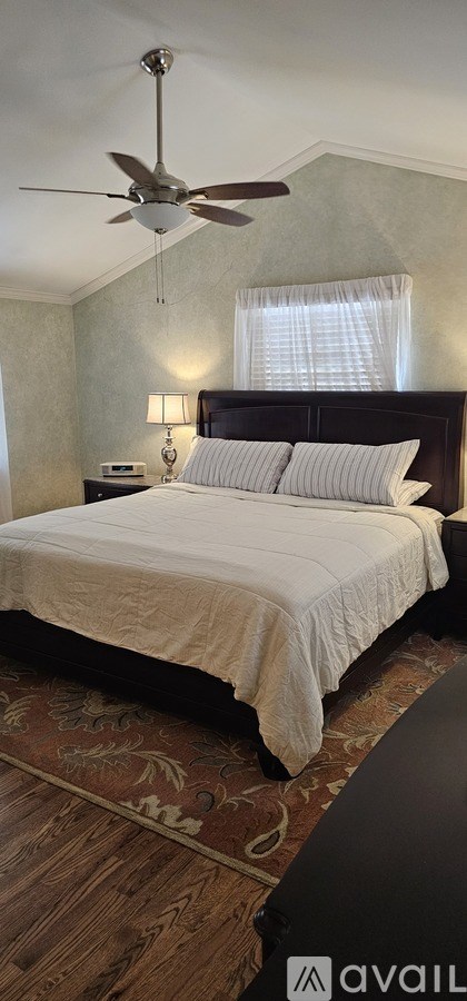 A bedroom with a bed, a ceiling fan, and a rug.