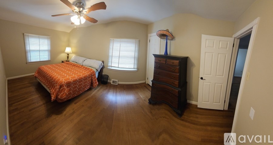 A bedroom with a bed, dresser, and window.