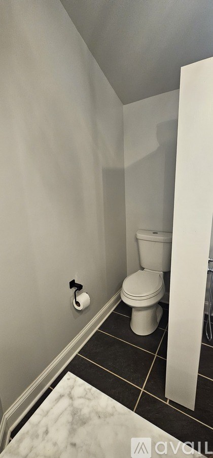 A white toilet in a bathroom with a white wall and a white door.