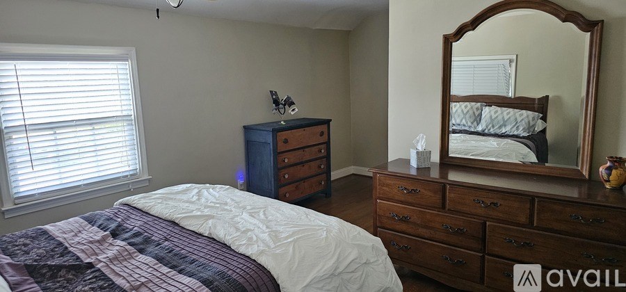 A bedroom with a bed, dresser, and mirror.