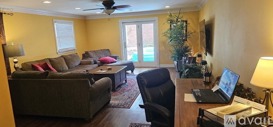 A living room with a brown couch and a black chair.