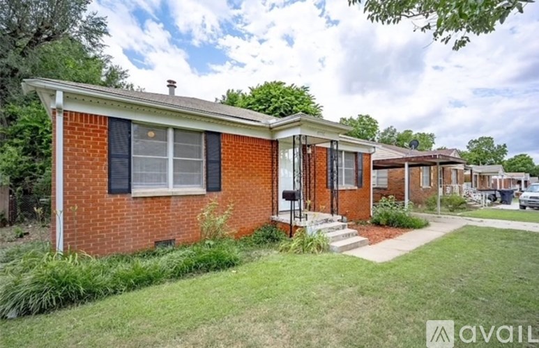 A red brick house with a white window and black shutters is for sale.