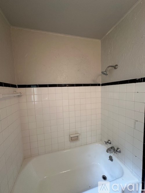 A white bathtub with black and white tiles on the wall.