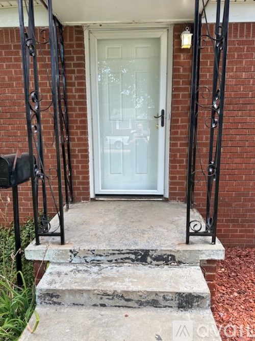 A white door is flanked by two black metal posts.