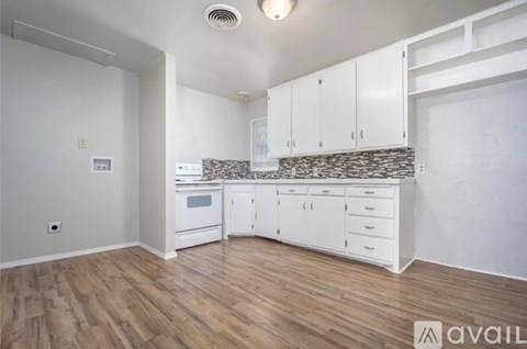 A kitchen with white cabinets and a stone backsplash.