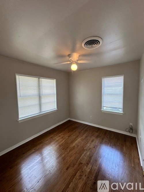 A room with wooden floors and two windows.