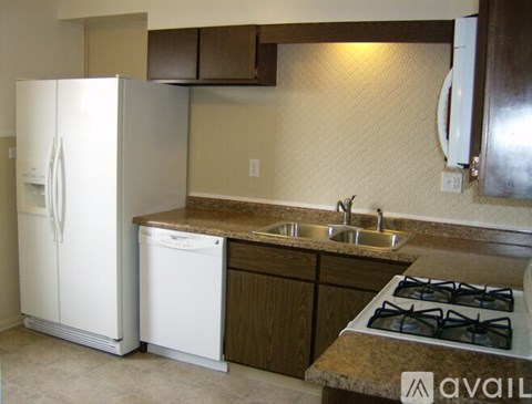 A kitchen with a white fridge, dishwasher and stove top.