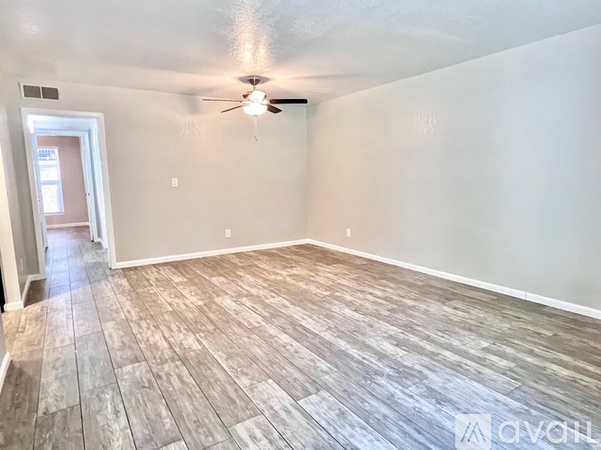 A room with a ceiling fan and wood flooring.