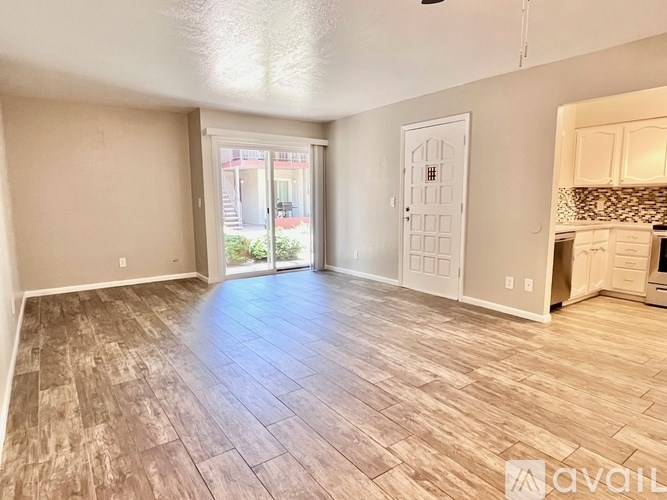 A spacious room with wood flooring and a sliding glass door leading outside.