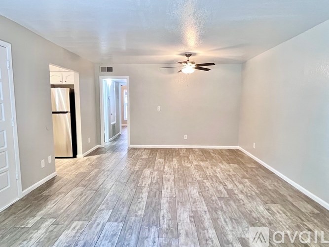 A spacious room with wood flooring and a ceiling fan.