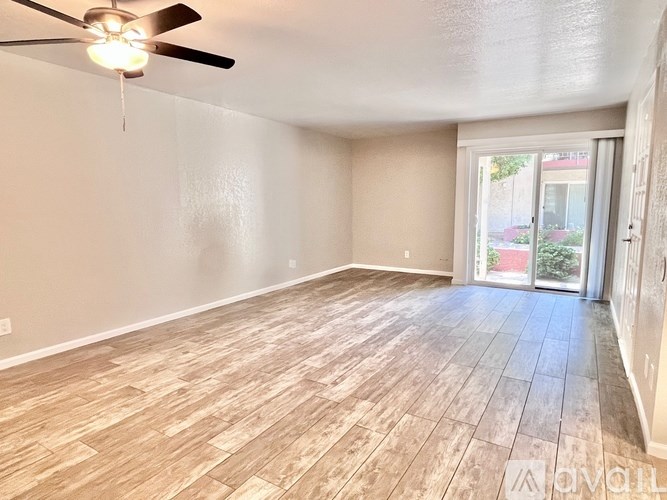 A room with a ceiling fan and wooden flooring.