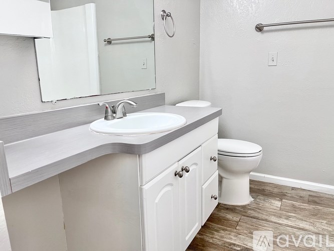 A white bathroom with a sink, toilet and mirror.