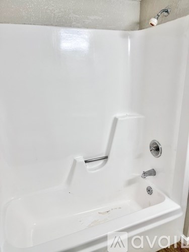 A white bathtub with a shower head and faucet.