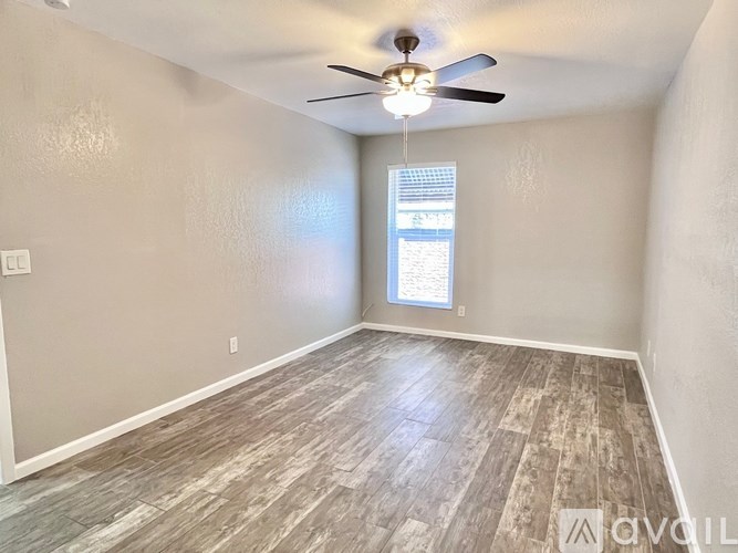 A room with a ceiling fan and a window with blinds.