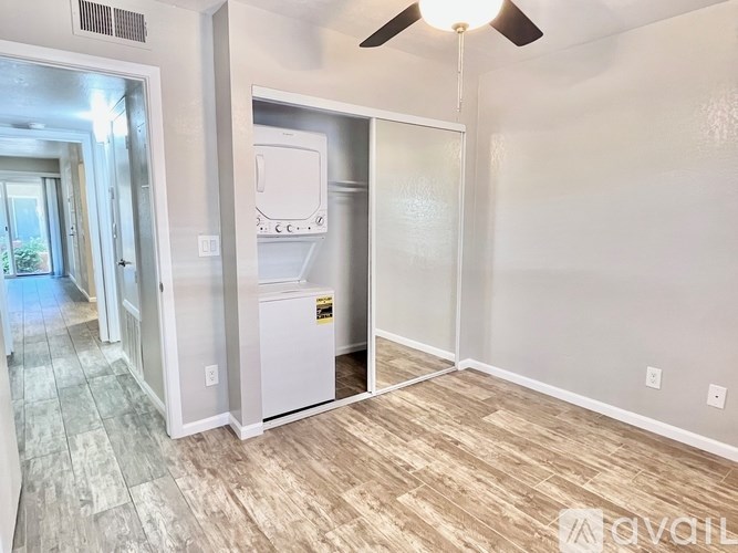 A room with a white fridge and a ceiling fan.