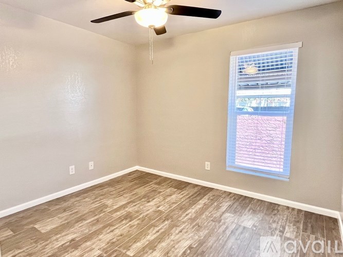 A room with a ceiling fan and a window with blinds.