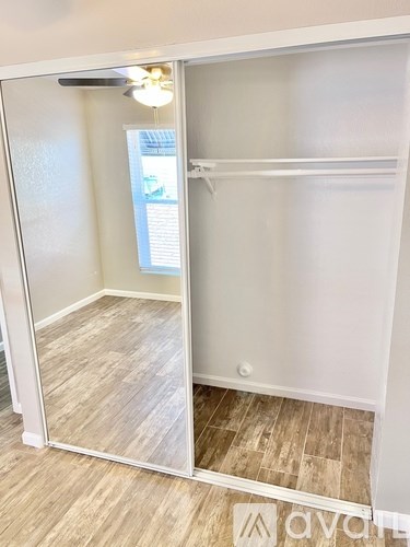 A room with a mirrored door and a wooden floor.