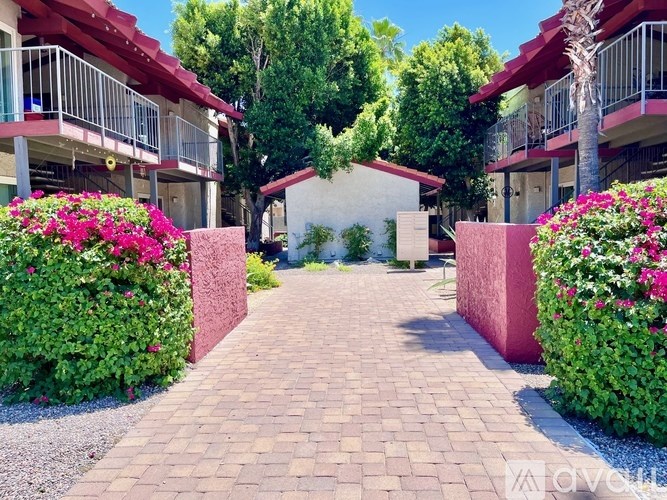 A red building with a balcony and a tree in front of it.