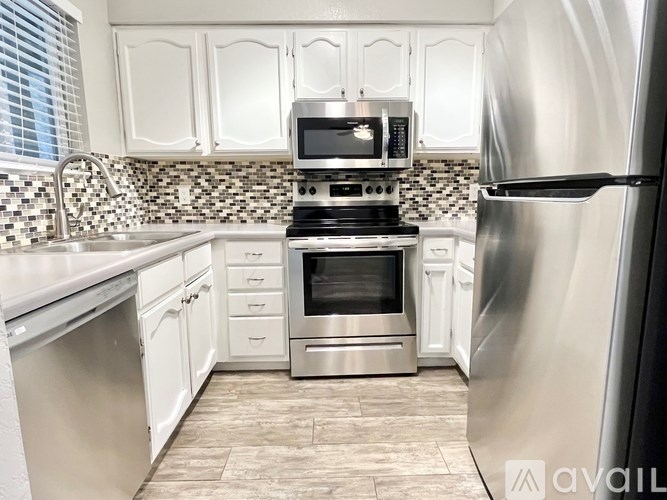 A kitchen with white cabinets and a stainless steel refrigerator.