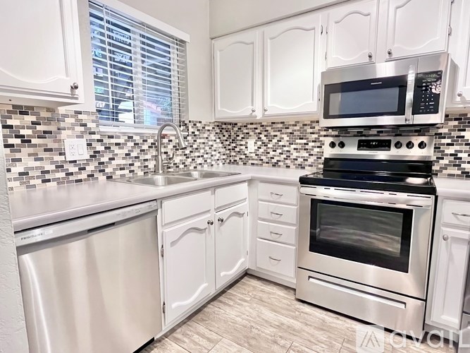 A kitchen with white cabinets and a black and white checkered backsplash.