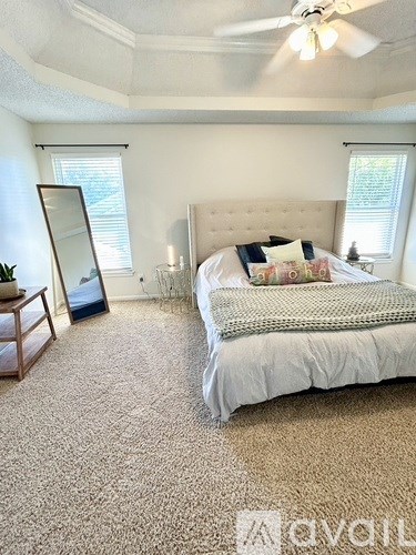 A bedroom with a large bed and a ceiling fan.