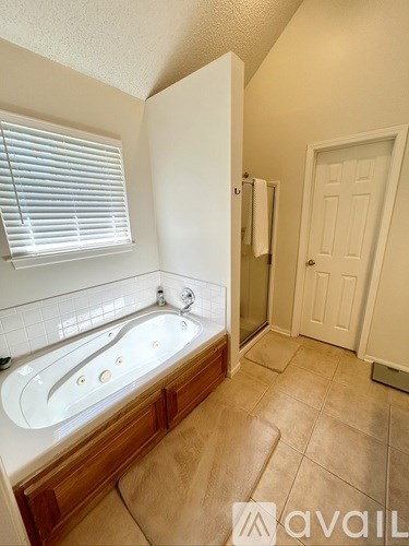 A bathroom with a tub and a window with blinds.