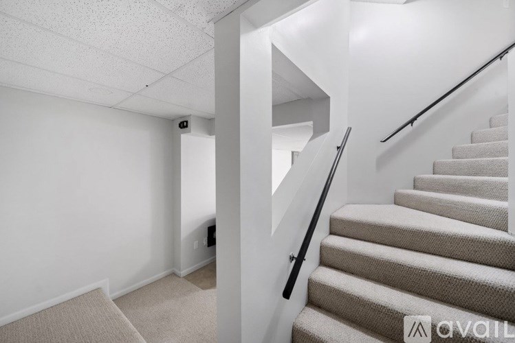 A staircase with a beige carpeted runner and a black handrail.