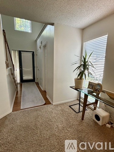 A carpeted hallway with a table and a plant.