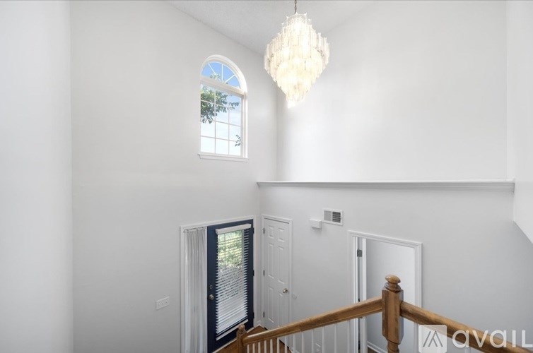 A chandelier hangs in a white room with a window and a door.