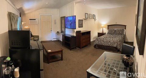 A living room with a television, a couch, a chair, and a coffee table.