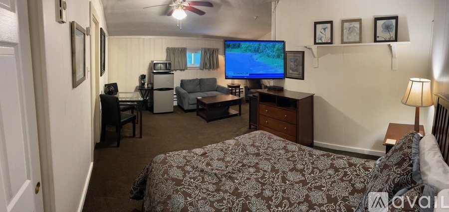 A bedroom with a bed, desk, and television.