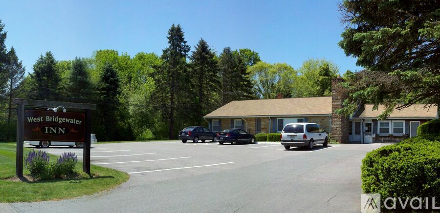 The parking lot of the West Bridgewater Inn is surrounded by trees.