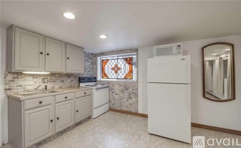 A kitchen with white cabinets and a white refrigerator.