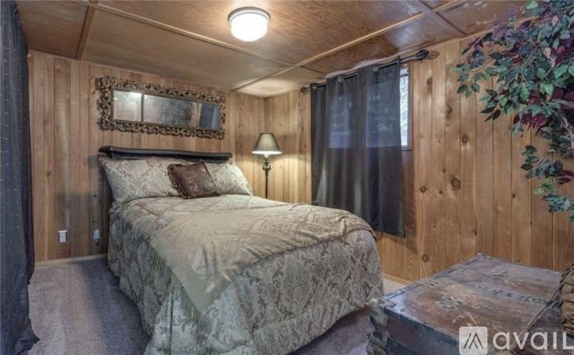 A bedroom with a bed, wooden walls, and a window with curtains.