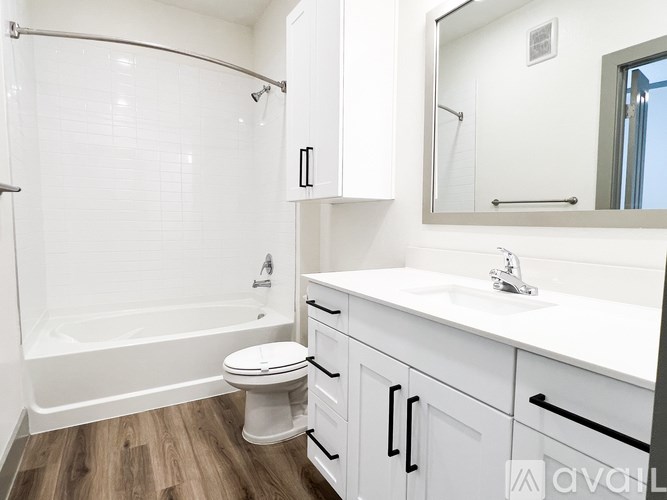 A white bathroom with a wooden floor and a white toilet.