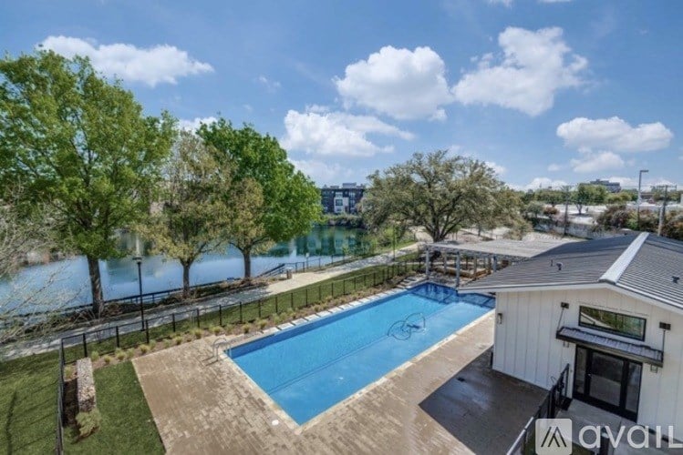 A pool surrounded by a fence and trees with a building in the background.