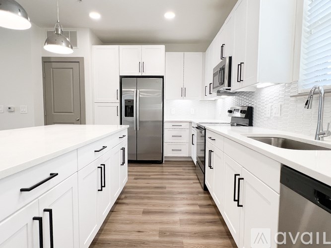 A modern kitchen with white cabinets and a wooden floor.