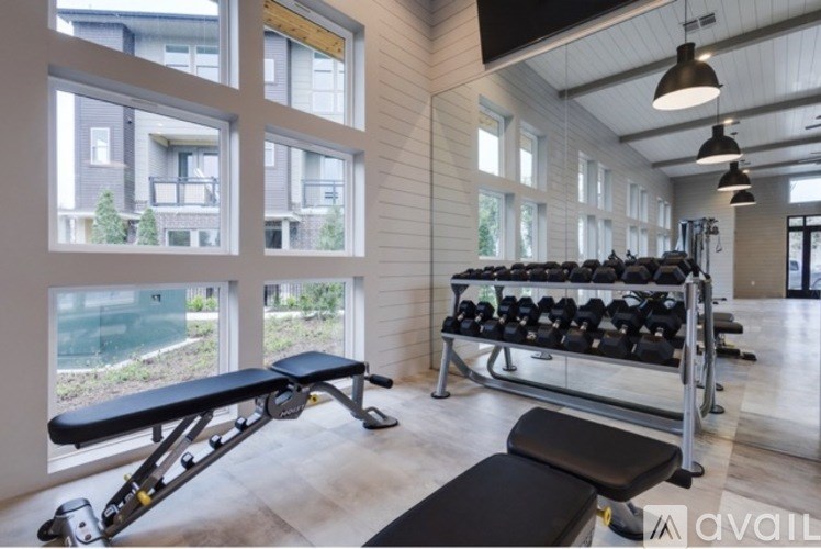 A gym with a bench, weights, and windows.